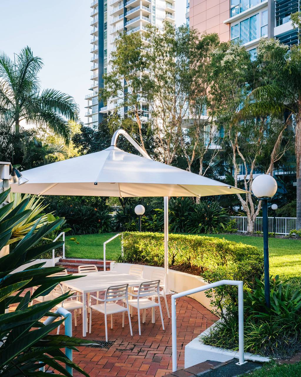 Garden courtyard with dining table and umbrella beneath tall trees