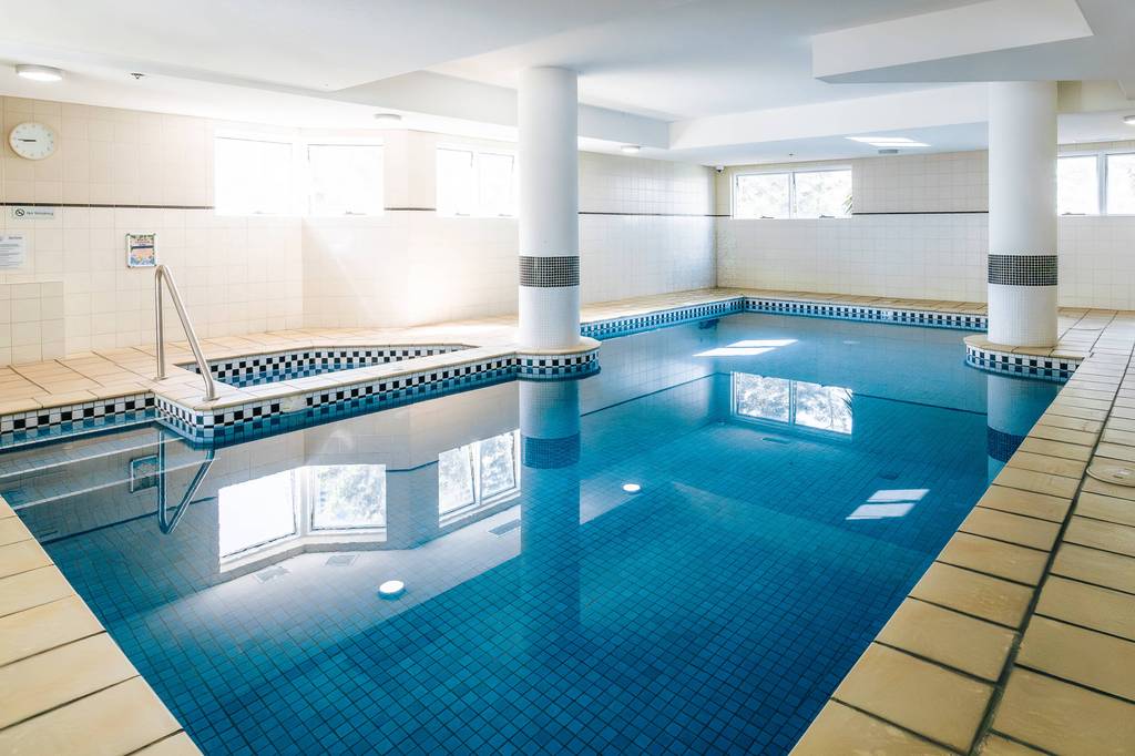 Indoor lap pool with tiled blue base and columns in bright light