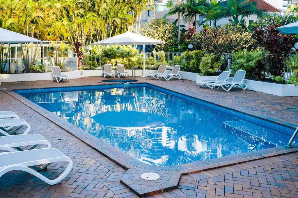 Heated outdoor pool at The Crest with loungers under a clear sky