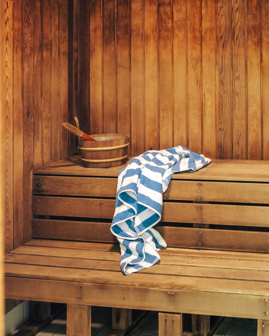 Sauna bench with striped towel and wooden bucket