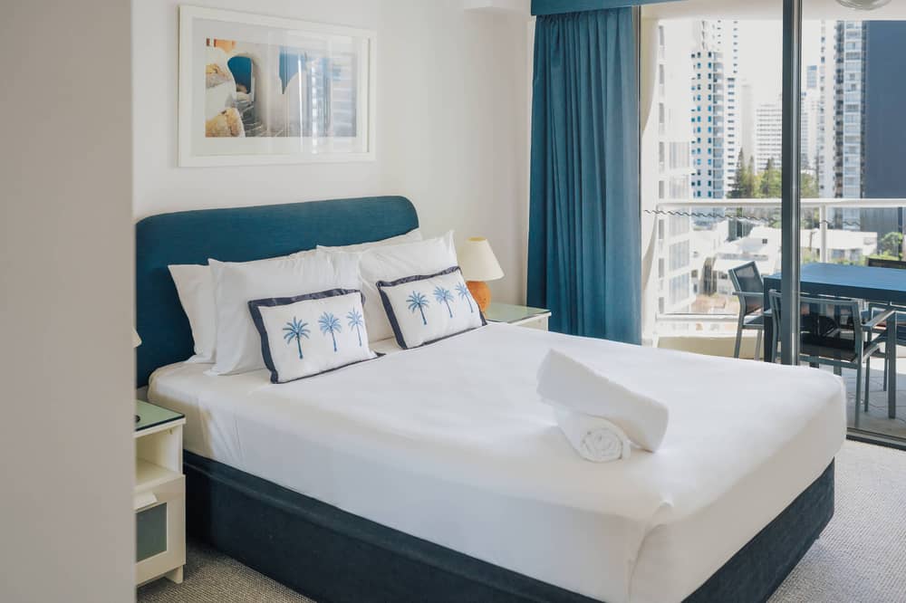 Bedroom with teal headboard and balcony door